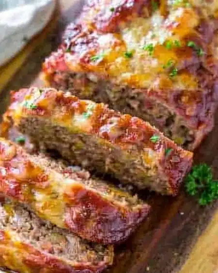 Delicious Traeger smoked meatloaf with melted cheese garnished with herbs