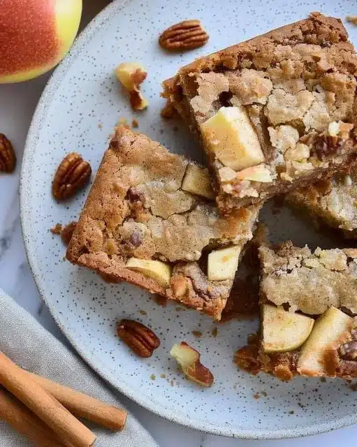 Delicious apple brownies topped with chocolate drizzle on a rustic table.