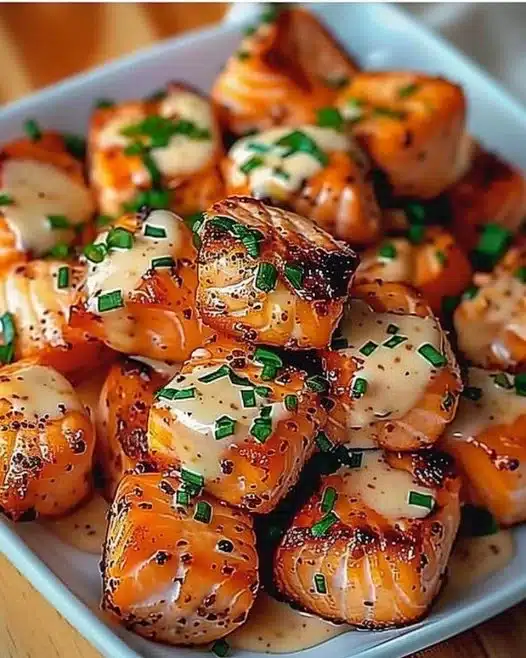 Bang Bang Salmon Bites served on a plate garnished with herbs