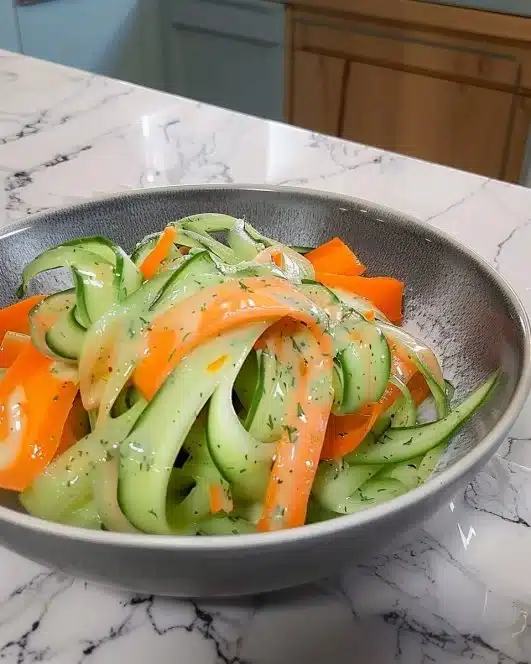 Colorful Carrot and Cucumber Ribbon Salad served in a bowl with fresh herbs
