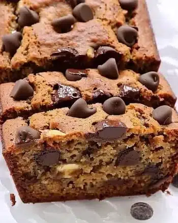 Slice of healthier chocolate chip banana bread on a plate with chocolate chips