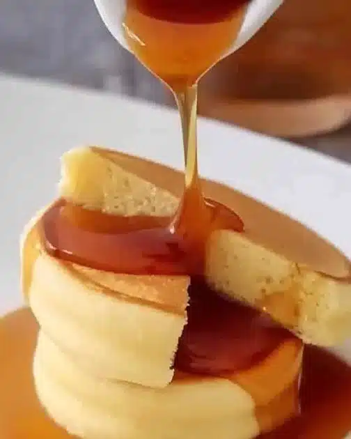 Deliciously fluffy Japanese pancakes stacked on a plate with syrup and berries