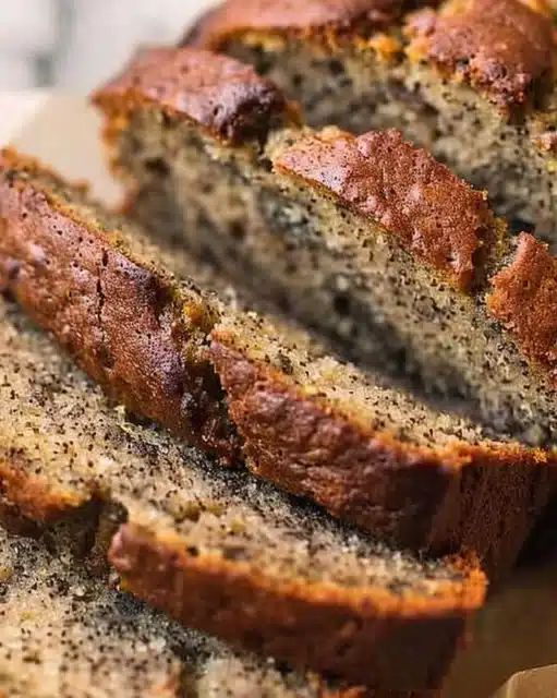Loaf of old-fashioned banana bread with slices cut and ripe bananas on the side