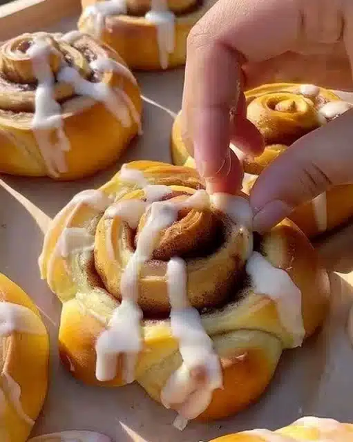 Pumpkin shaped cinnamon rolls with cream cheese frosting on a plate