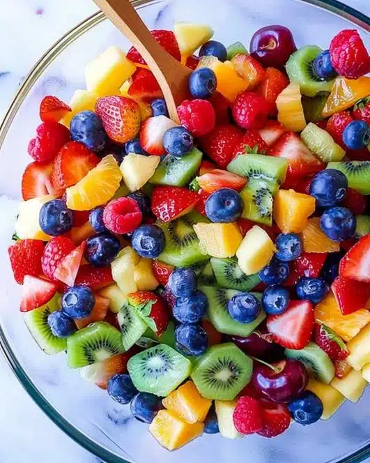 Colorful rainbow fruit salad with various fresh fruits in a bowl