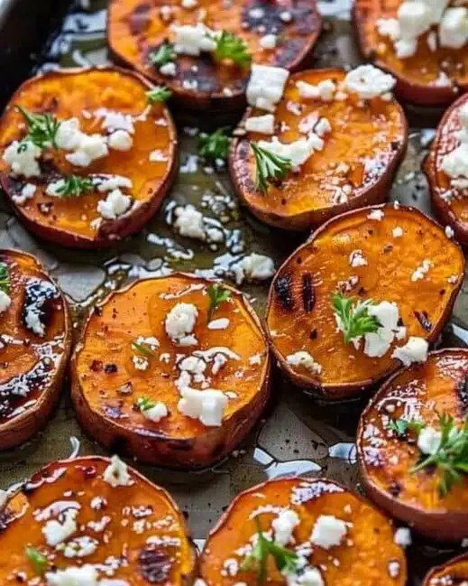 Plate of roasted sweet potato rounds drizzled with honey and sprinkled with feta cheese.