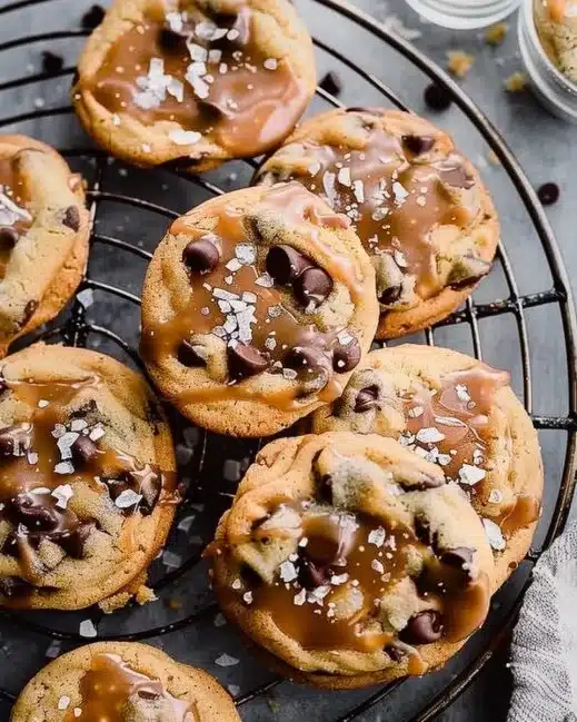 Freshly baked Salted Caramel Chocolate Chip Cookies on a cooling rack.