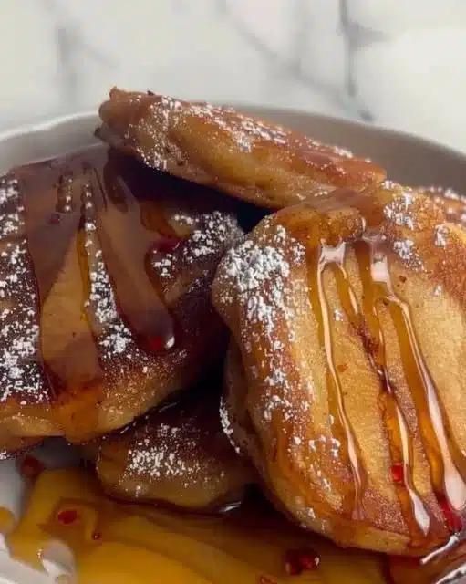 Fluffy sliced apple pancakes topped with fresh apple slices and syrup.
