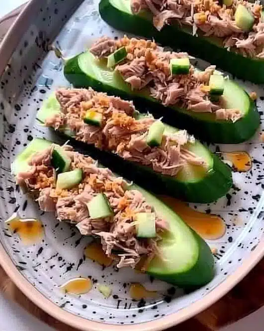 Spicy tuna cucumber boats topped with fresh herbs and sesame seeds