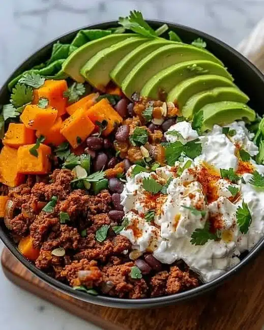 Delicious sweet potato taco bowl topped with fresh vegetables and herbs.