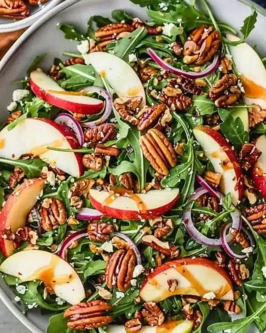 Apple Arugula Salad topped with Maple Pecans in a bowl