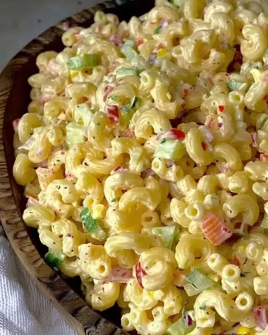 Creamy homemade macaroni salad served in a bowl with vegetables and dressing.