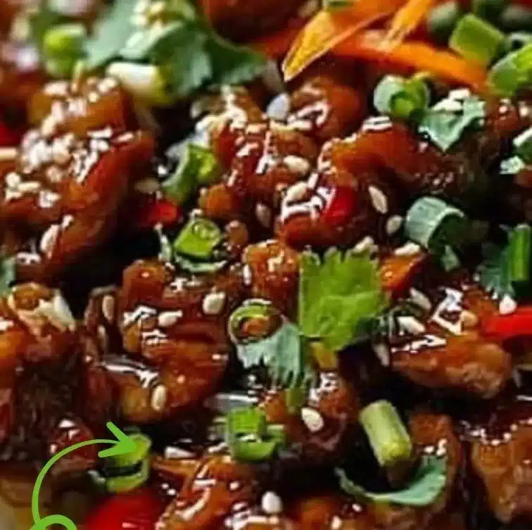 A plate of crispy chilli beef fried rice garnished with fresh vegetables