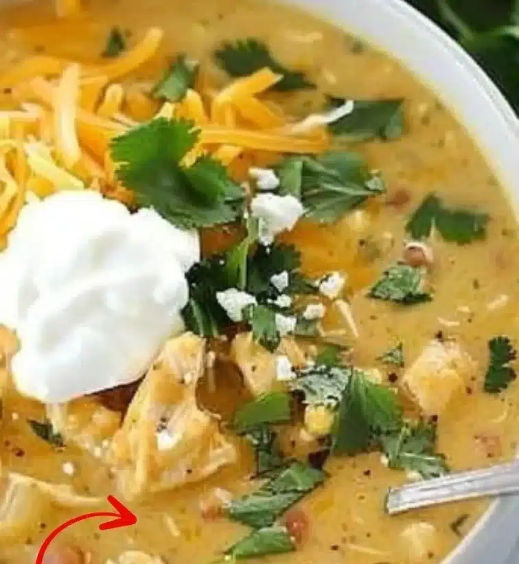 Bowl of Green Chile Chicken Enchilada Soup garnished with cilantro and lime.