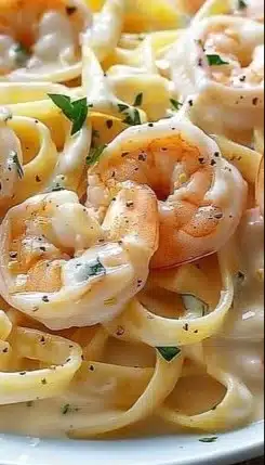 Delicious Shrimp Alfredo dish served in a bowl with creamy sauce and garnished herbs.