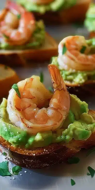 Delicious Shrimp Avocado Crostini topped with fresh herbs and served on toasted bread.