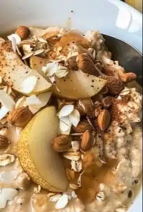 Bowl of warm spiced pear oatmeal topped with nuts and cinnamon