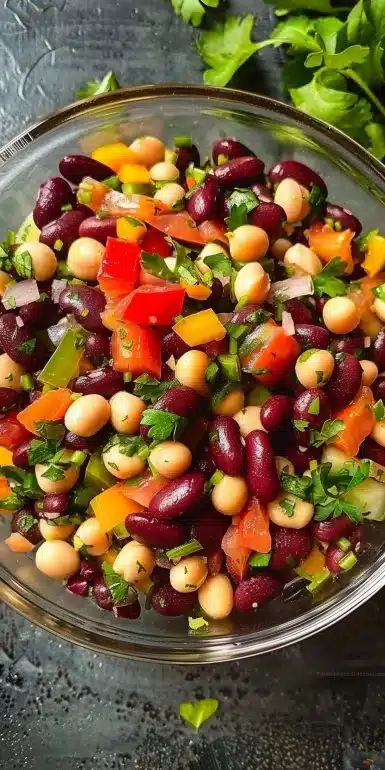 High protein three bean salad with fresh vegetables and beans in a bowl