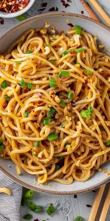 Bowl of flavorful Vegan Garlic Noodles topped with fresh herbs and garlic.